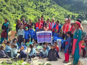 Barn og voksne i en nepalsk fjellandsby mottar skolestøtte og klær fra Helping Hands for Nepal.